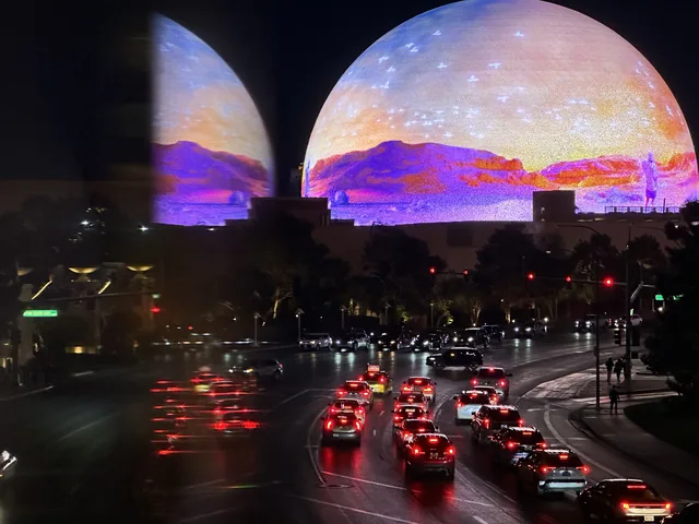The illuminated Las Vegas Sphere above a street with evening traffic.