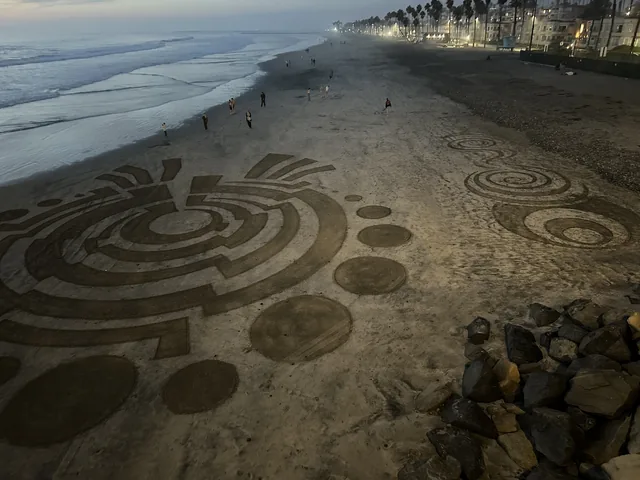Circular patterns drawn in the sand along Oceanside beach.