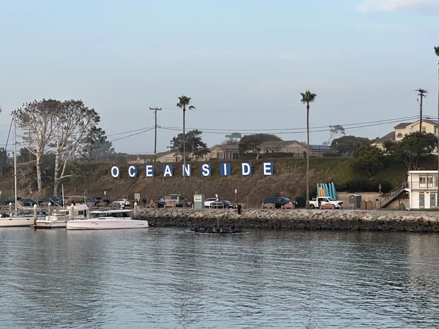 Boats moored beside the Oceanside sign along the harbor.