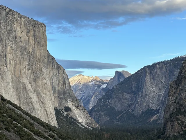 Yosemite Valley framed by granite cliffs beneath a blue sky.
